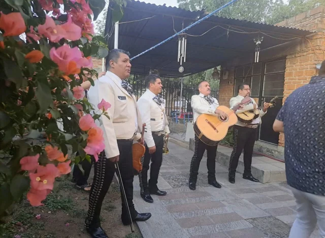 Integrantes de Mariachi Insignia interpretando música en un jardín